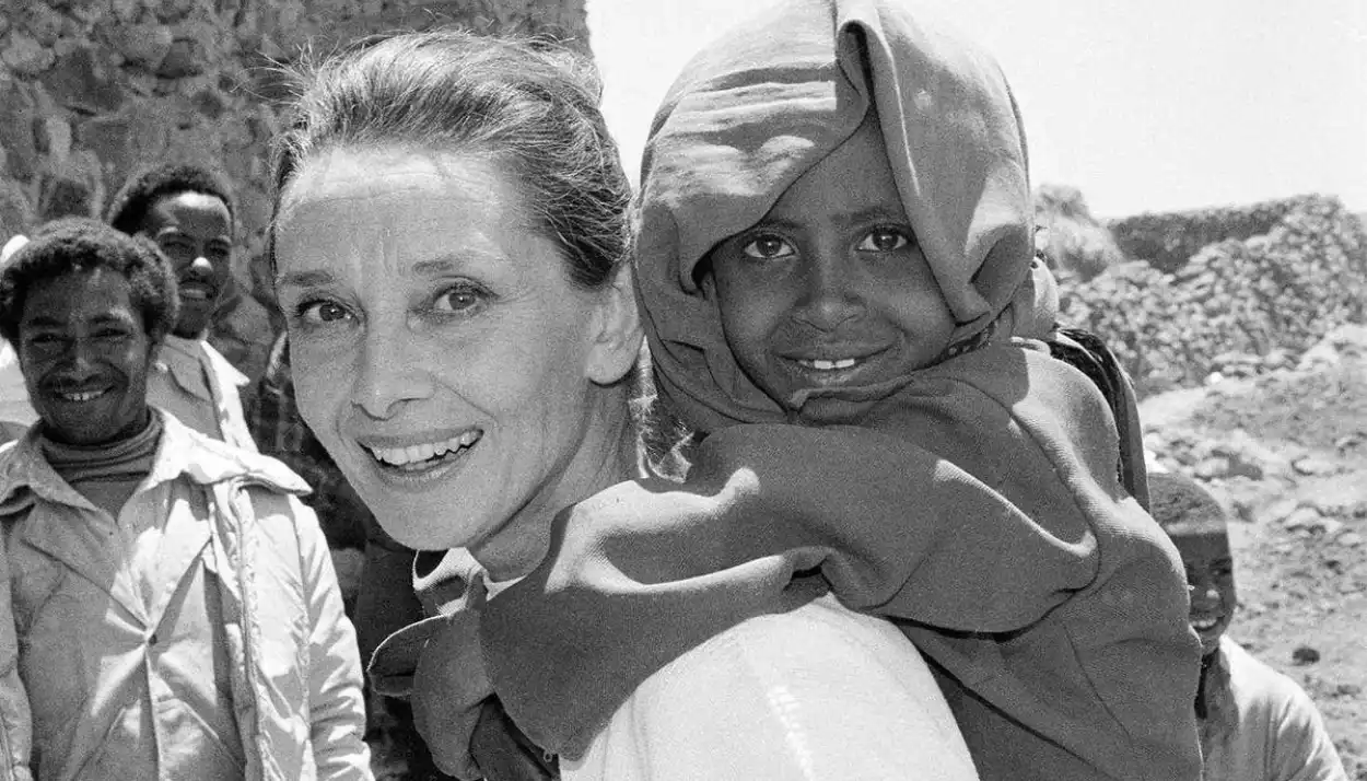 Audrey Hepburn with a child on her back, in one of her missions for UNICEF