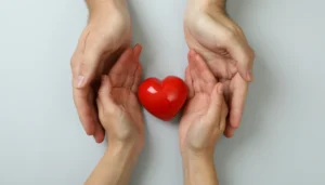 four hands surrounding a figure of a heart
