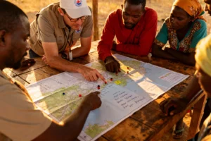 Field team collaborating with local community on social impact measurement using participatory evaluation methods in rural development project